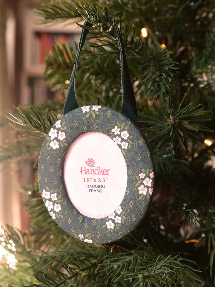 Round hanging fabric picture frame with green floral design on a Christmas tree
