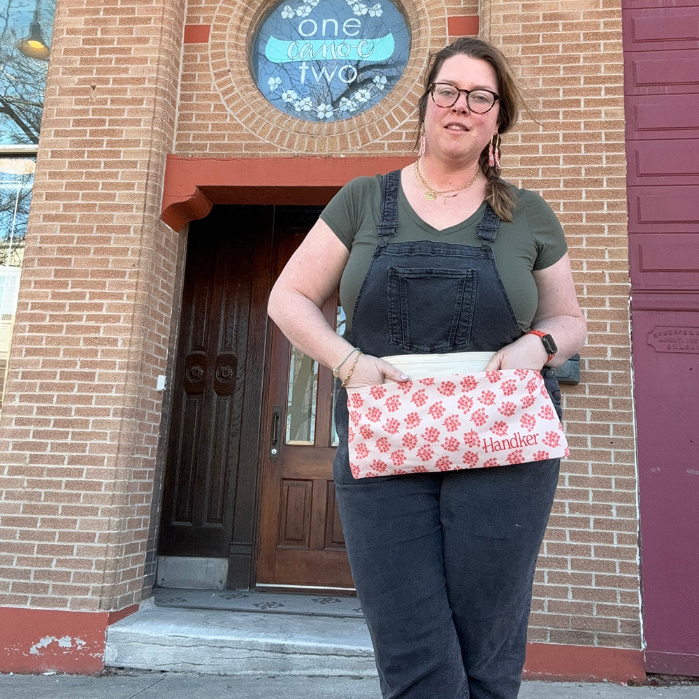 Person standing in front of a brick building holding a patterned bag