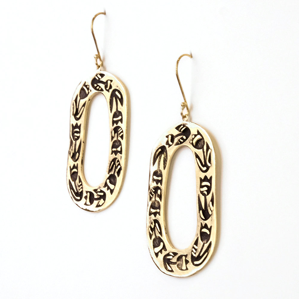 Oval-shaped gold earrings with intricate black patterns