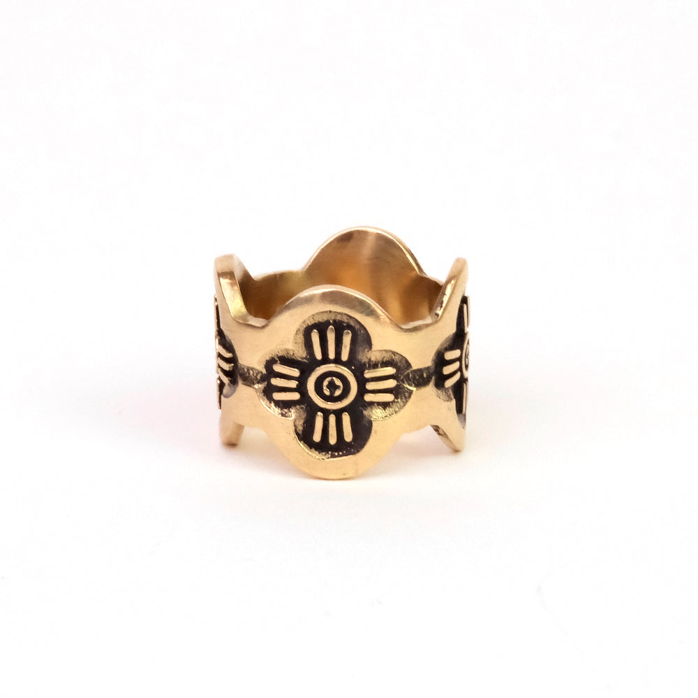 Gold ring with black engraved designs on a white background