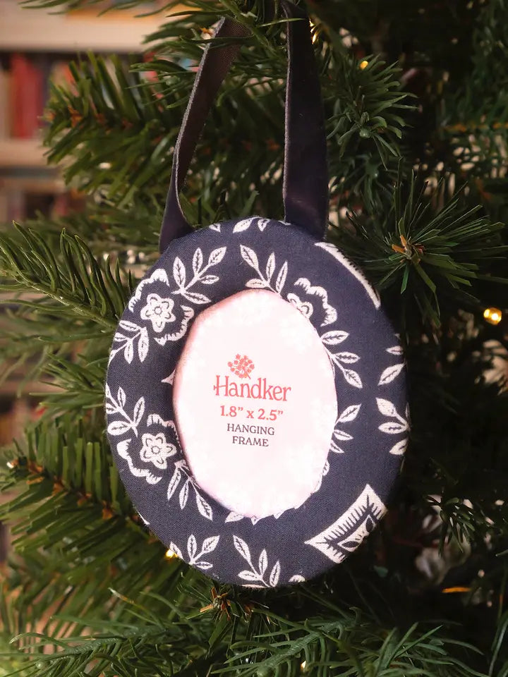 Round hanging fabric picture frame with navy floral design on a Christmas tree