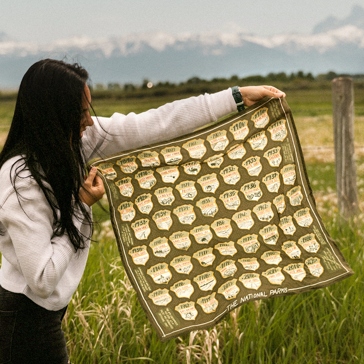 Person holding a green national park logos  bandana in a field