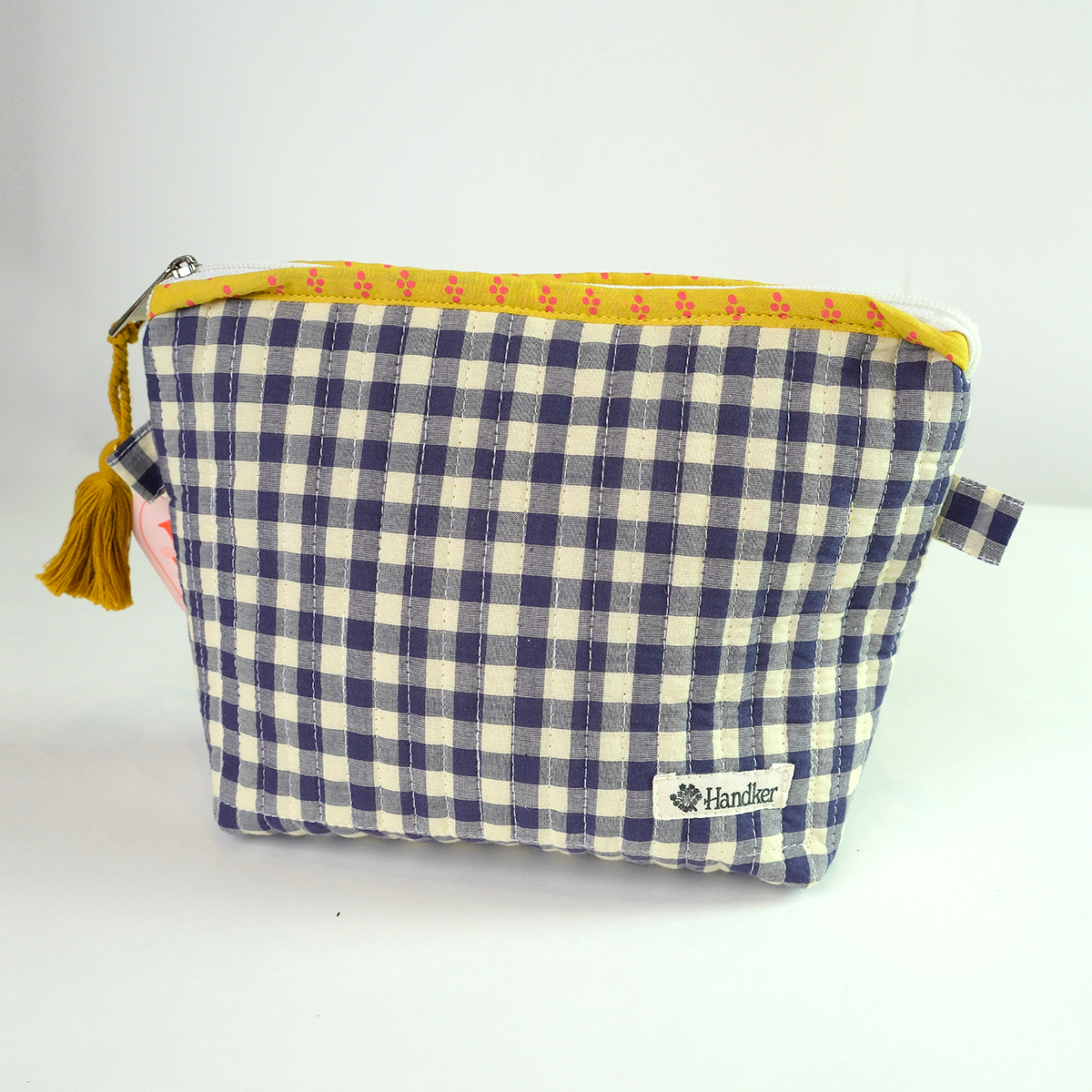 Blue and white checkered pouch with yellow trim and tassel on a white background