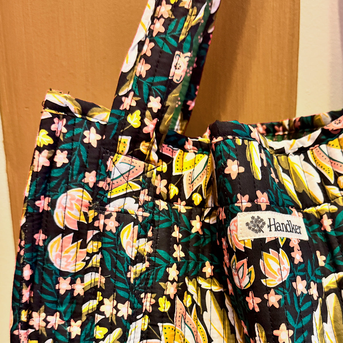 Floral-patterned tote with 'Handker' label on a wooden surface