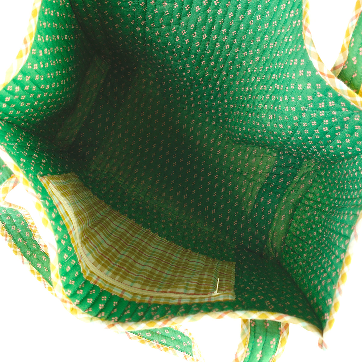 Close-up of a tote bag with a green fabric interior and a yellow plaid pocket