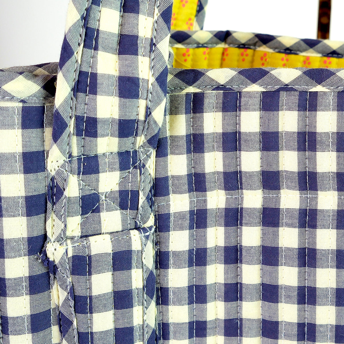 Detail view of Teddy Quilted Tote strap and body showcasing navy and cream checkered quilted cotton with yellow floral lining