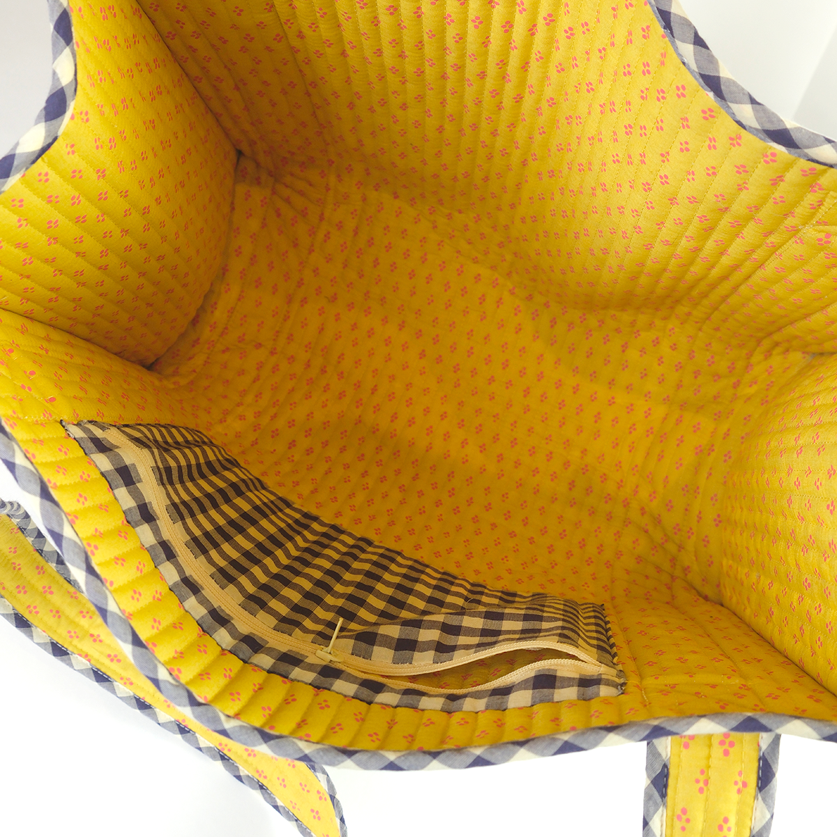 Close-up of a yellow fabric with checkered pattern pocket inside a bag.