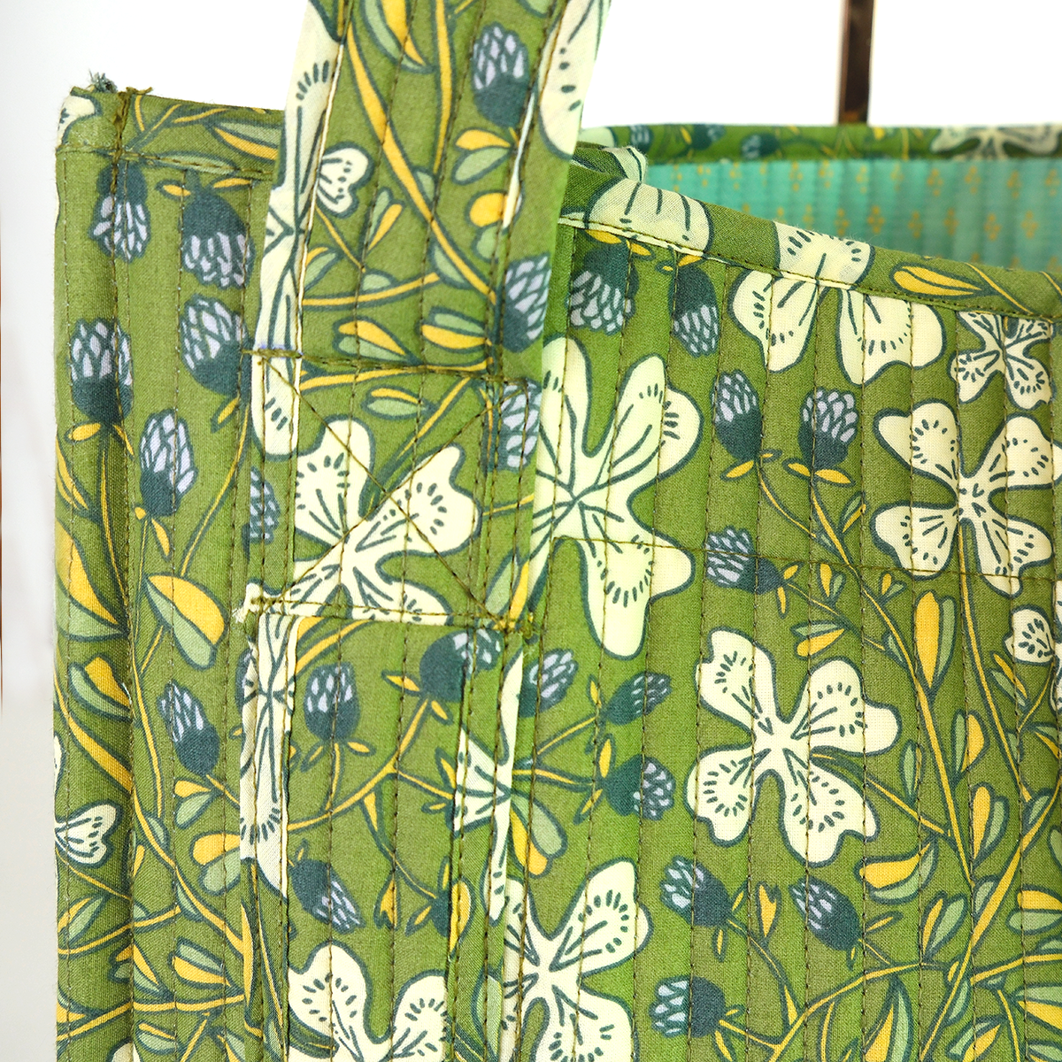 Close up of a green floral patterned fabric tote with white flowers and blue accents