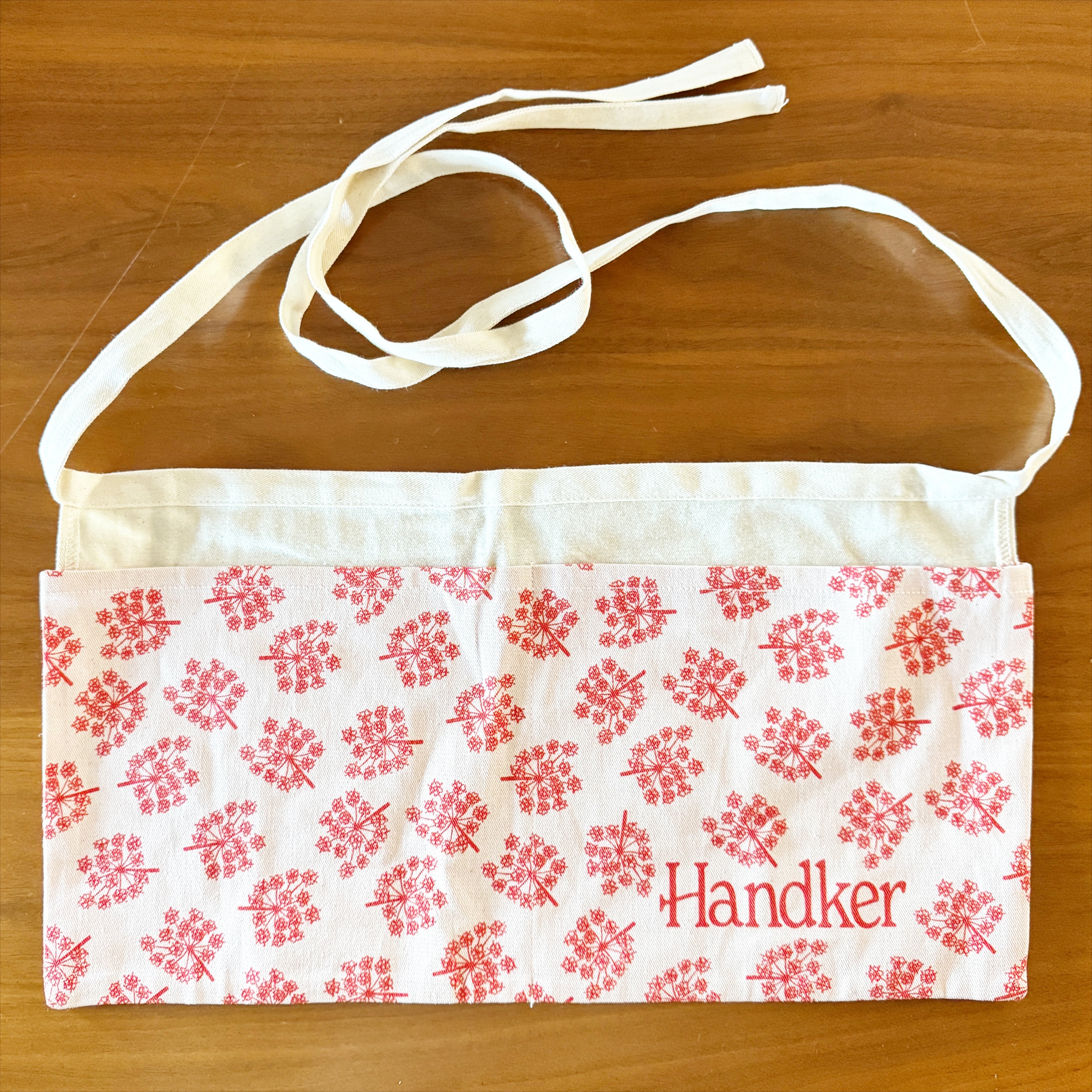 White and red floral-patterned fabric pouch with 'Handker' embroidered on it