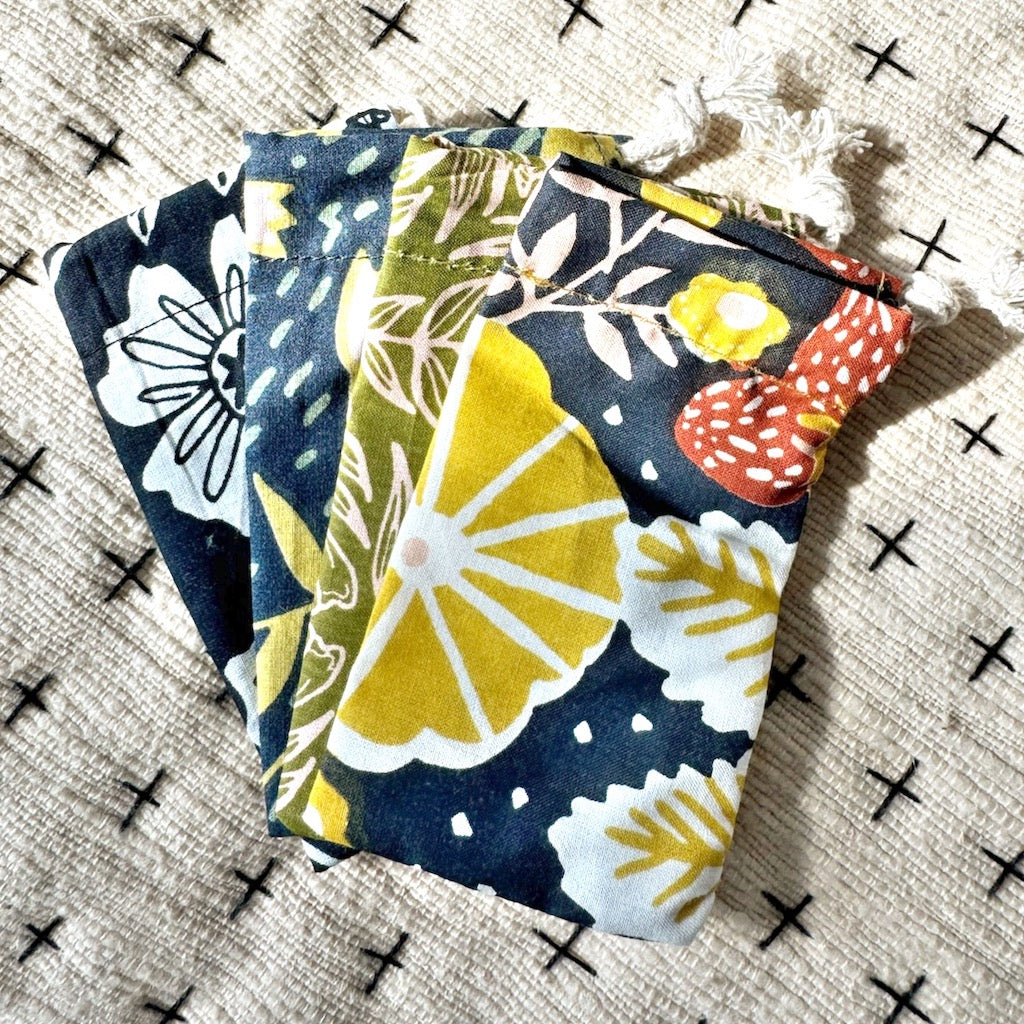 Colorful floral drawstring pouches on a patterned surface.