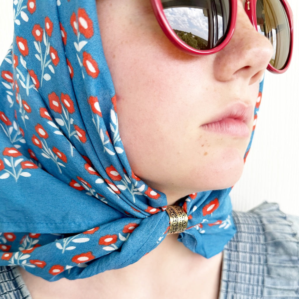 Person wearing red sunglasses and a blue floral scarf, bandana, bandanna, or handkerchief