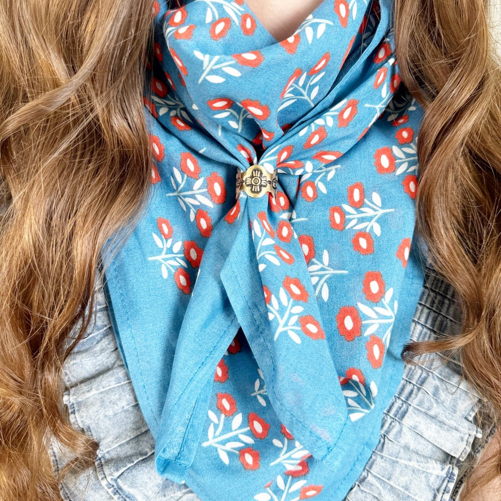 Person wearing a blue floral scarf with red and white patterns.