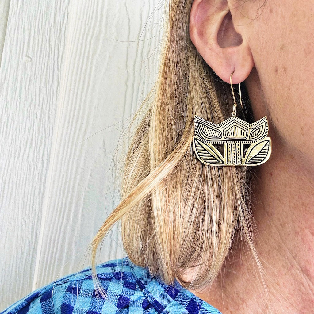 Woman wearing decorative geometric earrings.