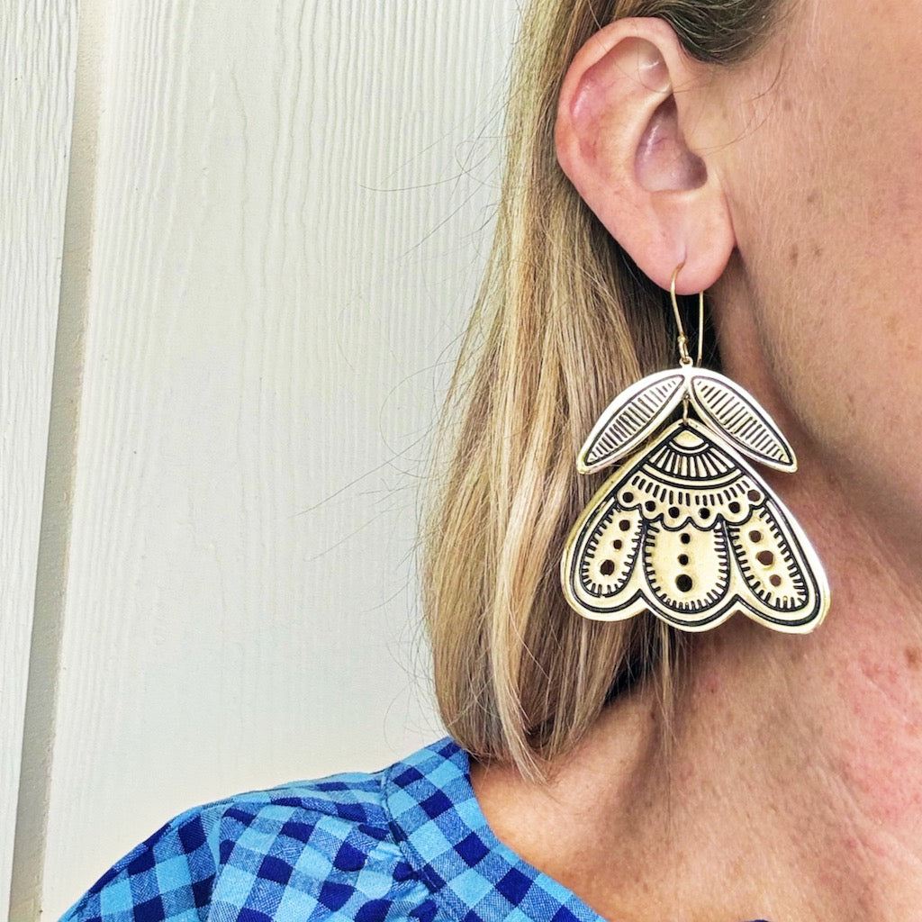 Close-up of woman wearing large moth-shaped earring.