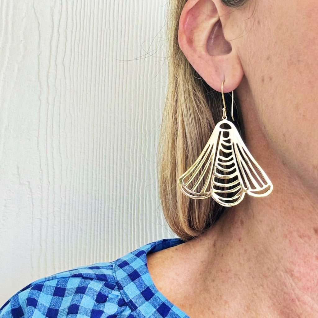 Close-up of a woman's ear wearing a stylish geometric gold earring