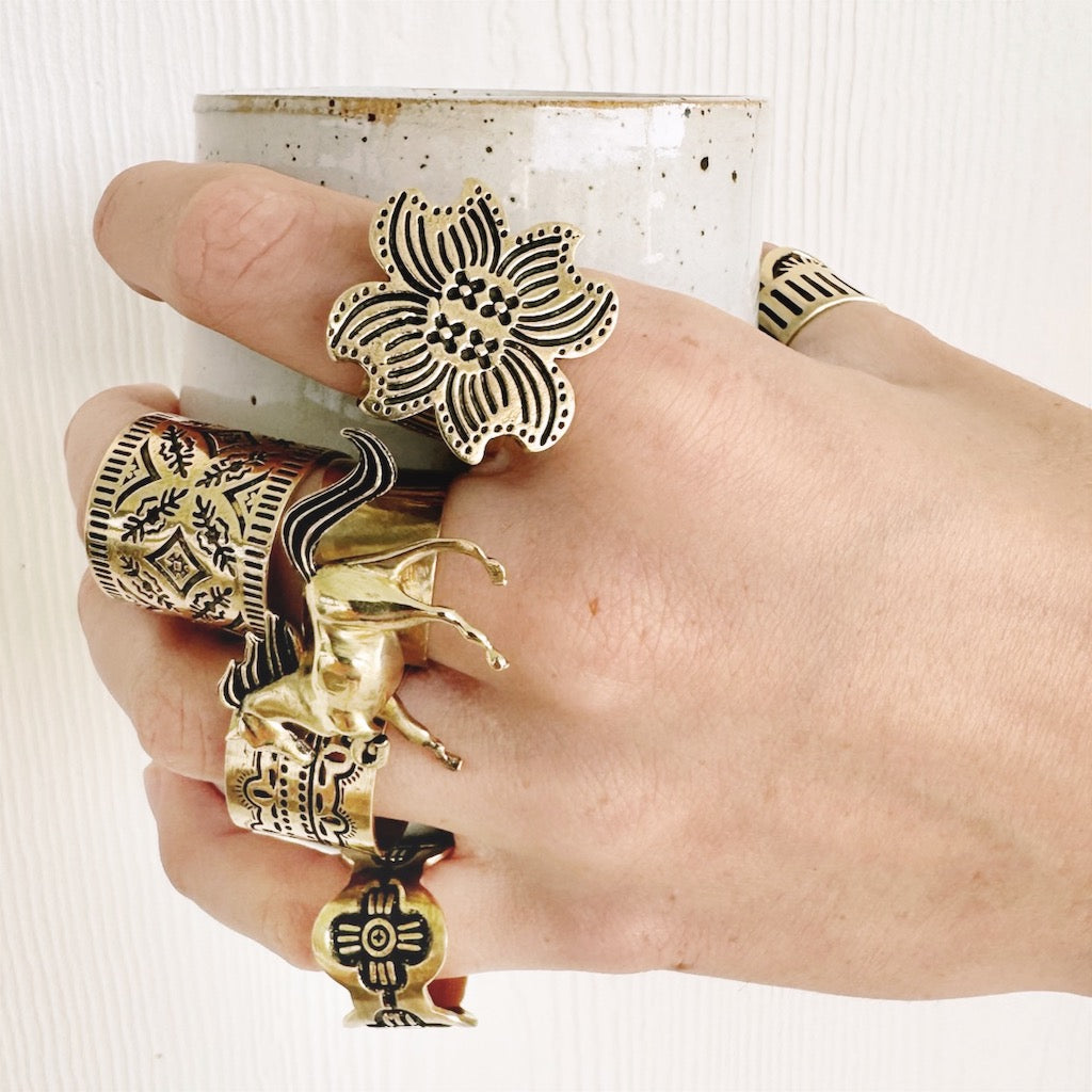 Hand adorned with large decorative rings holding a ceramic cup