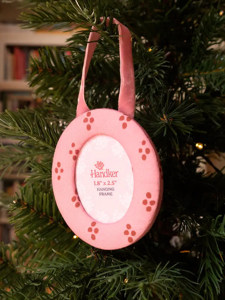 Round hanging fabric picture frame with pink and red dotted design on a Christmas tree