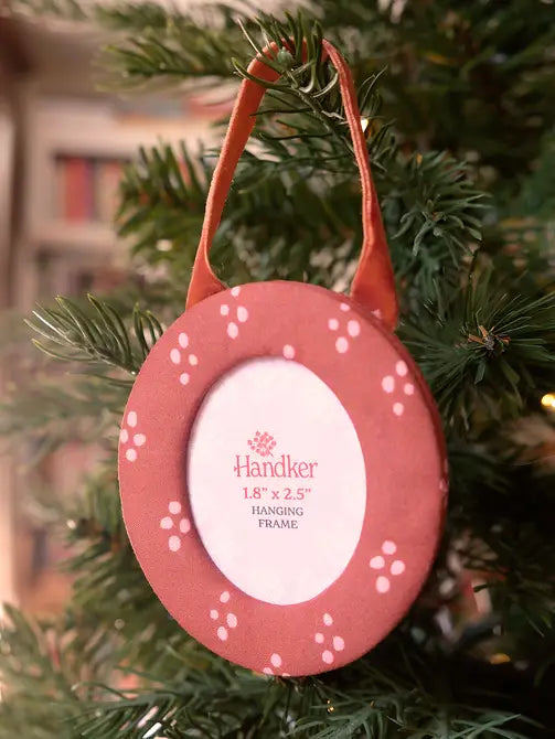 Round hanging fabric picture frame with red and pink dotted design on a Christmas tree
