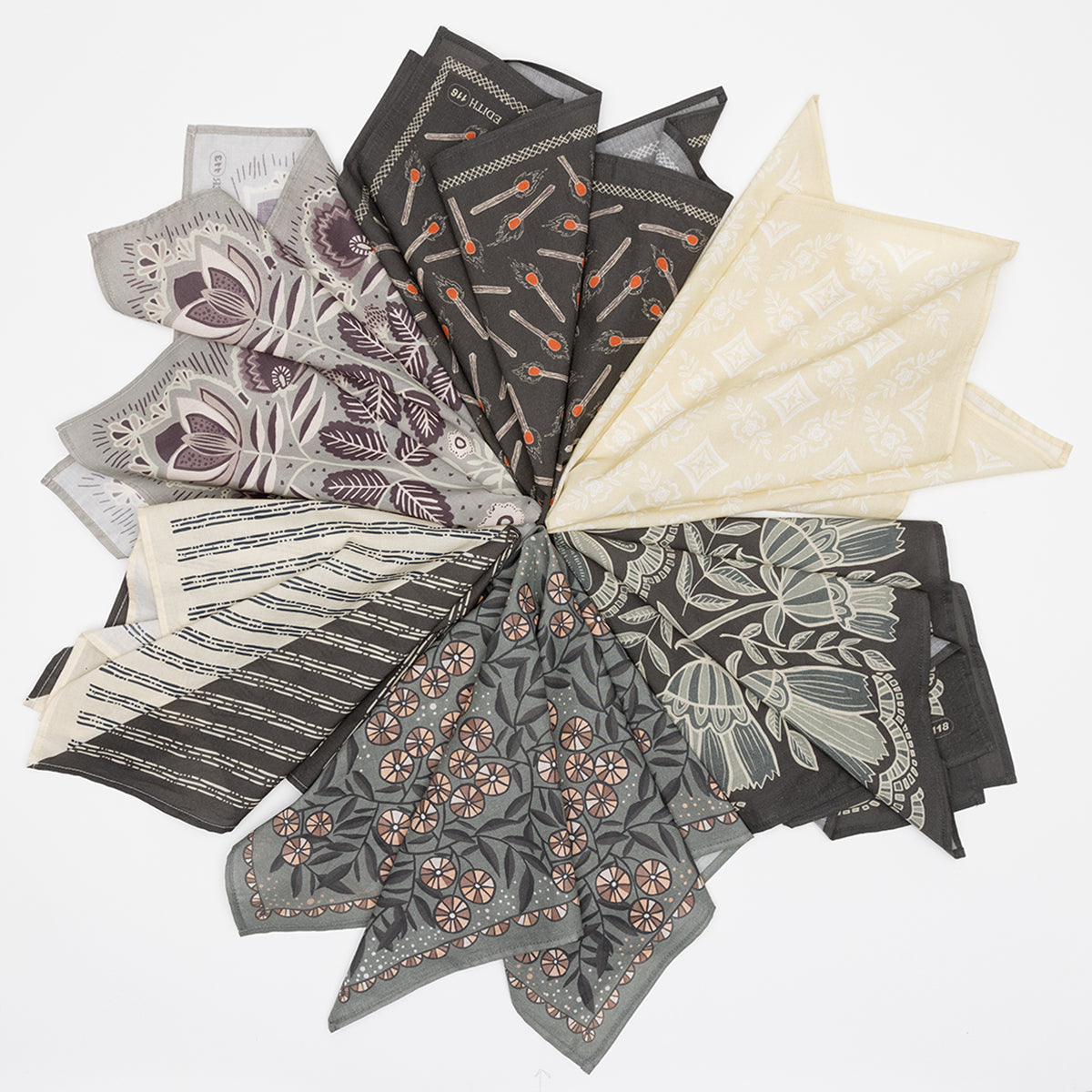 Overhead view of folded bandanas showcasing floral and geometric prints in warm gray, cream, and mauve on white background